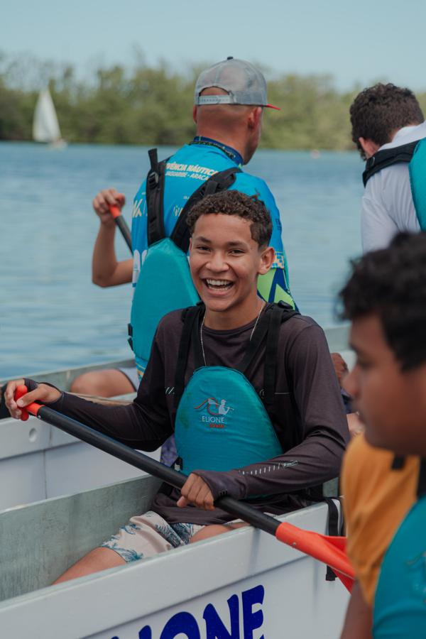 Jovem sorri remando na canoa havaiana