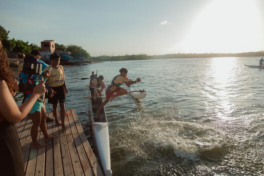Participante mergulha do píer ao lado de uma canoa
